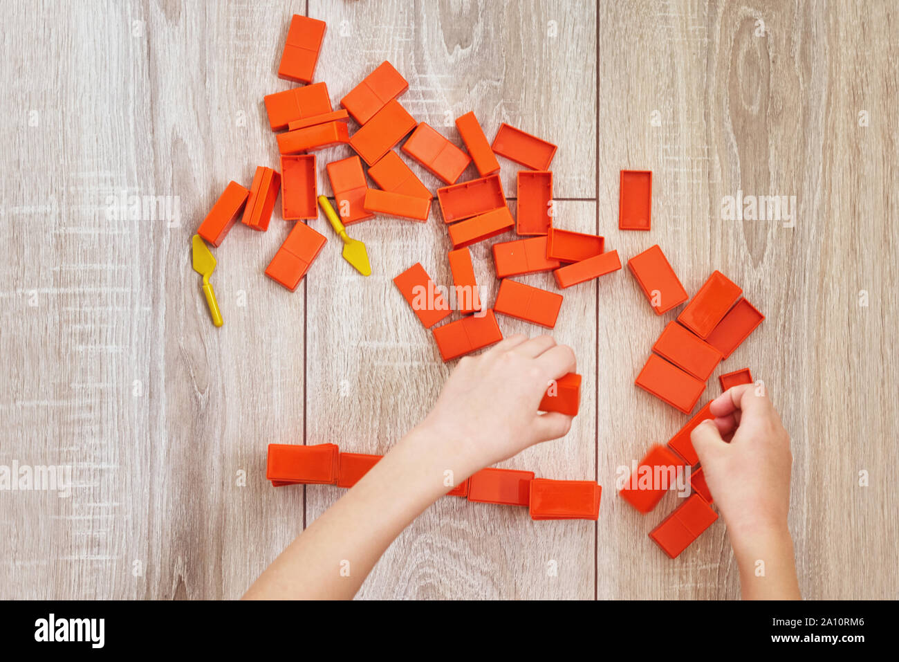 Vista superiore del bambino le mani giocando con orange toy mattoni. Concetto di kid lerning e l'istruzione. Baby tempo libero con sviluppo di giocattoli Foto Stock
