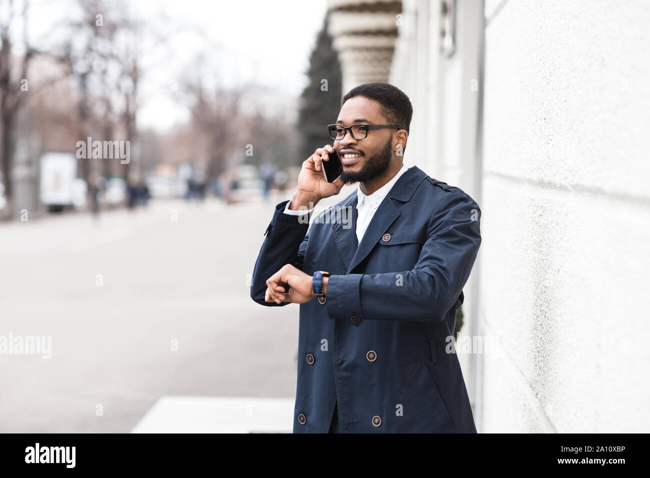 Manager parlando al cellulare e in attesa di un collega Foto Stock