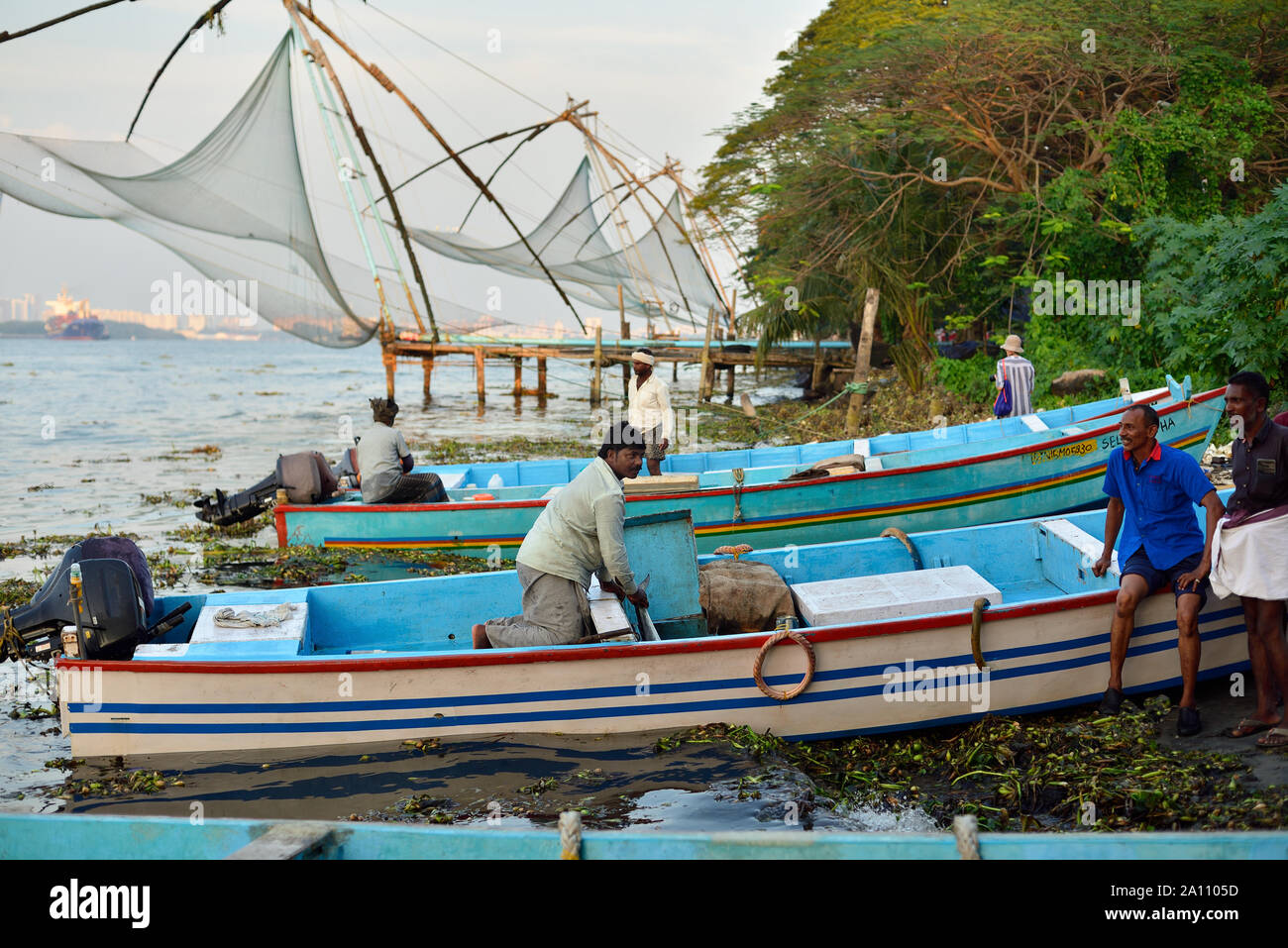 KOCHIN, Kerala, India - 01 dicembre 2018:i pescatori areunloading pesci dalla barca, in background cinese e netto di un turista, Cochin, India. Foto Stock