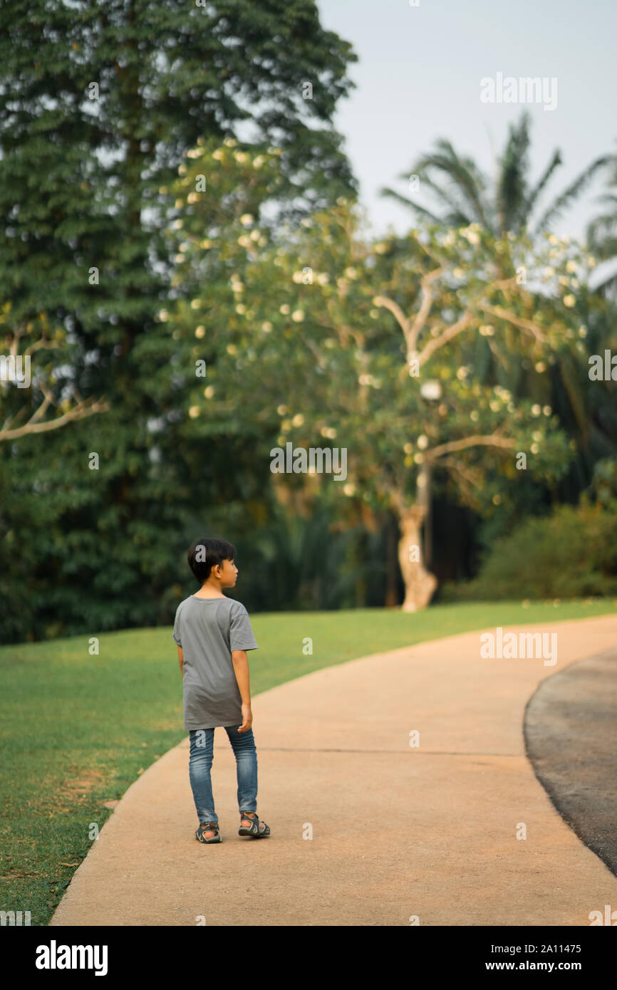 Asian giovane ragazzo a camminare da sola nel parco. Foto Stock
