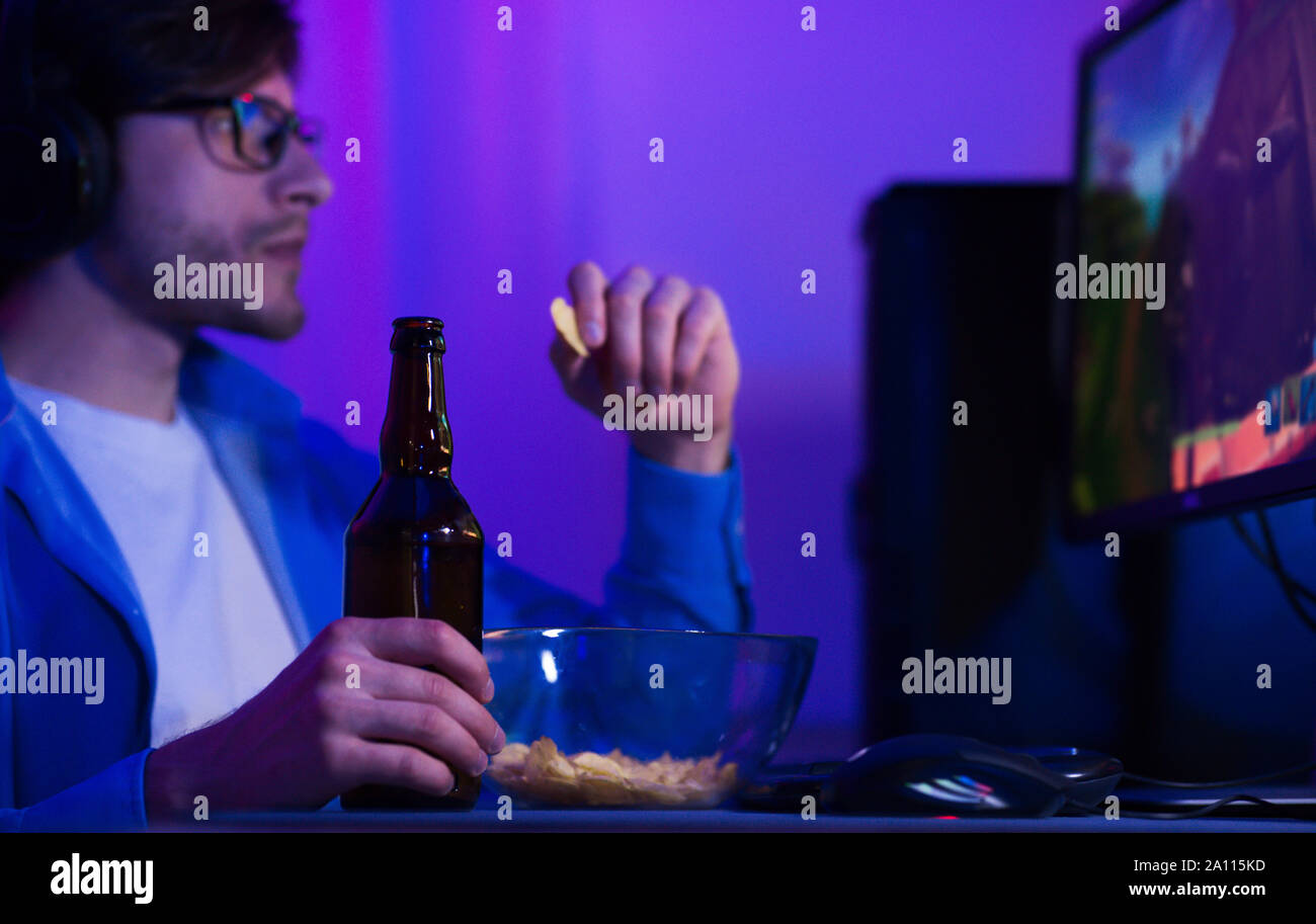 Concentrato gamer giochi sul computer e bere birra Foto Stock