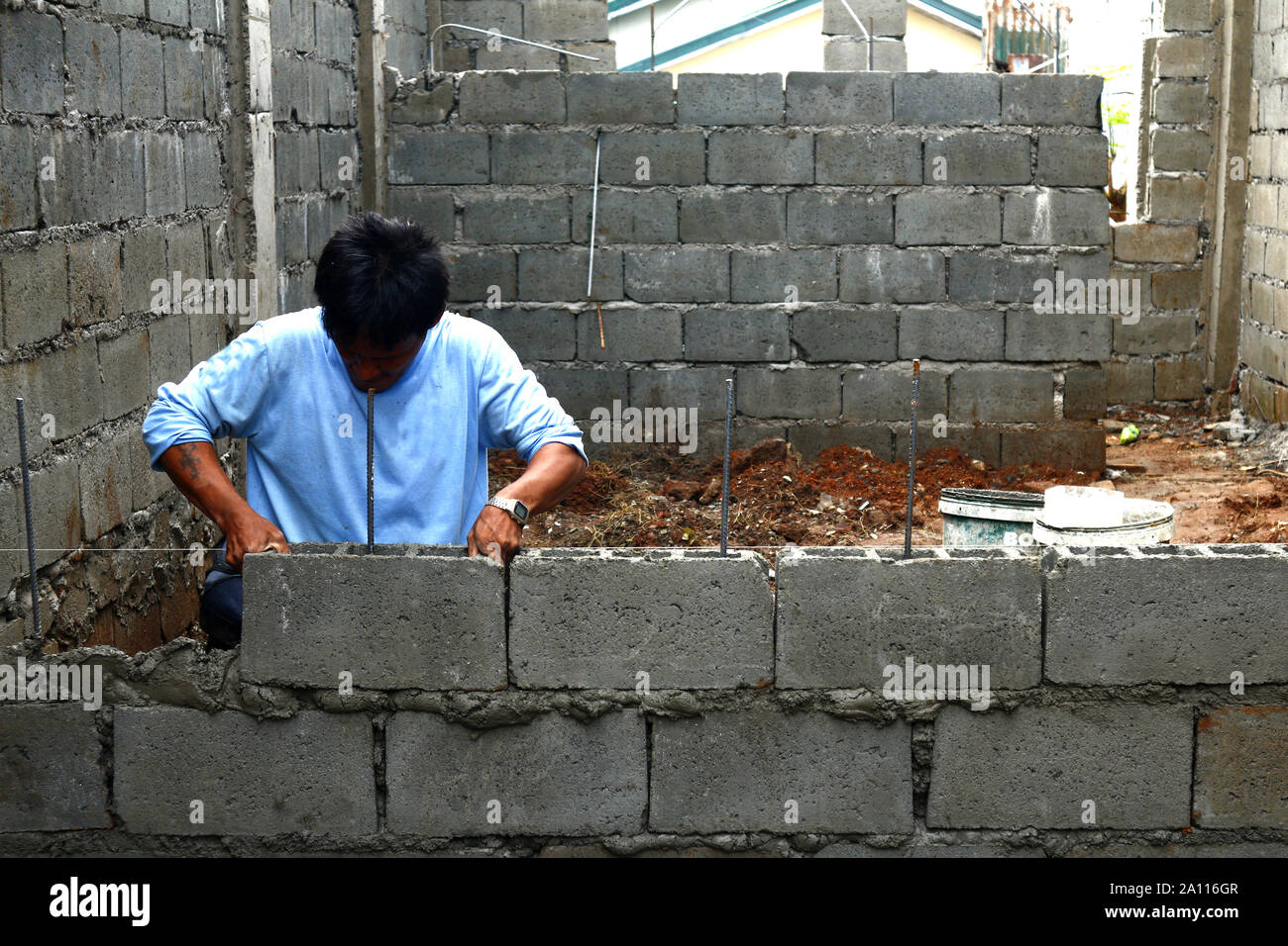 ANTIPOLO City, Filippine - 17 settembre 2019: lavoratore edile pile di blocchi di cava per costruire parete alla costruzione di casa residenziale. Foto Stock