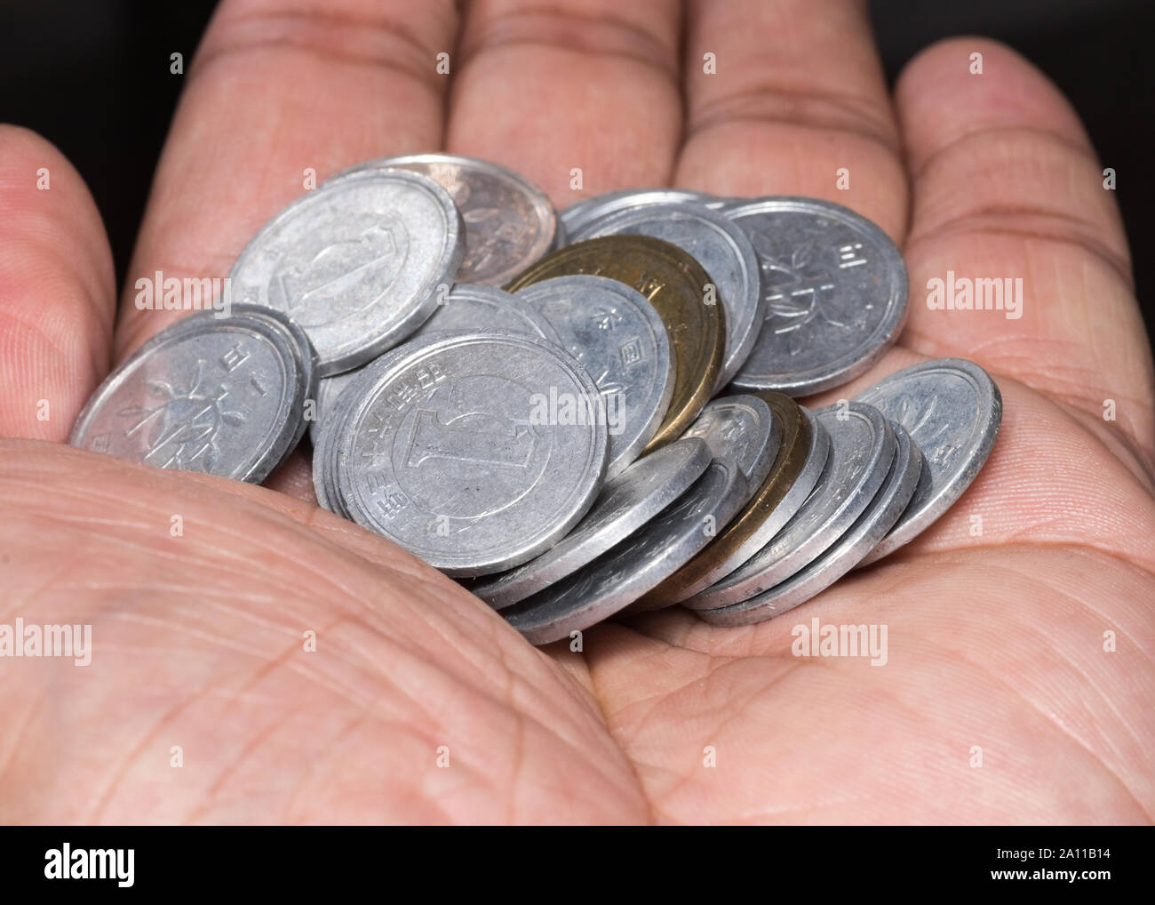 Una mano che tiene un mazzetto di giapponese minore quantità di monete. Foto Stock