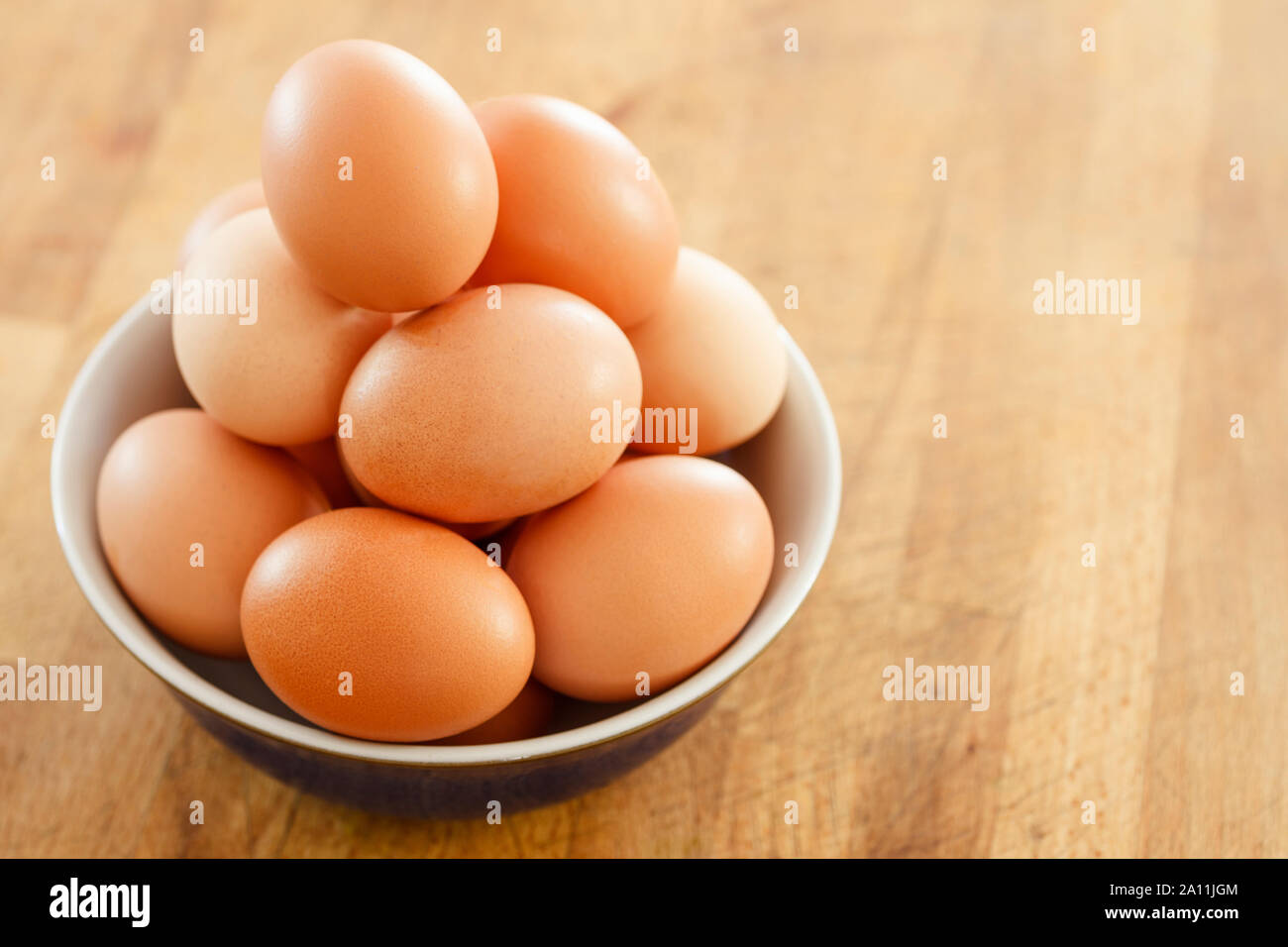 Ciotola di uova di galline su una superficie in legno Foto Stock
