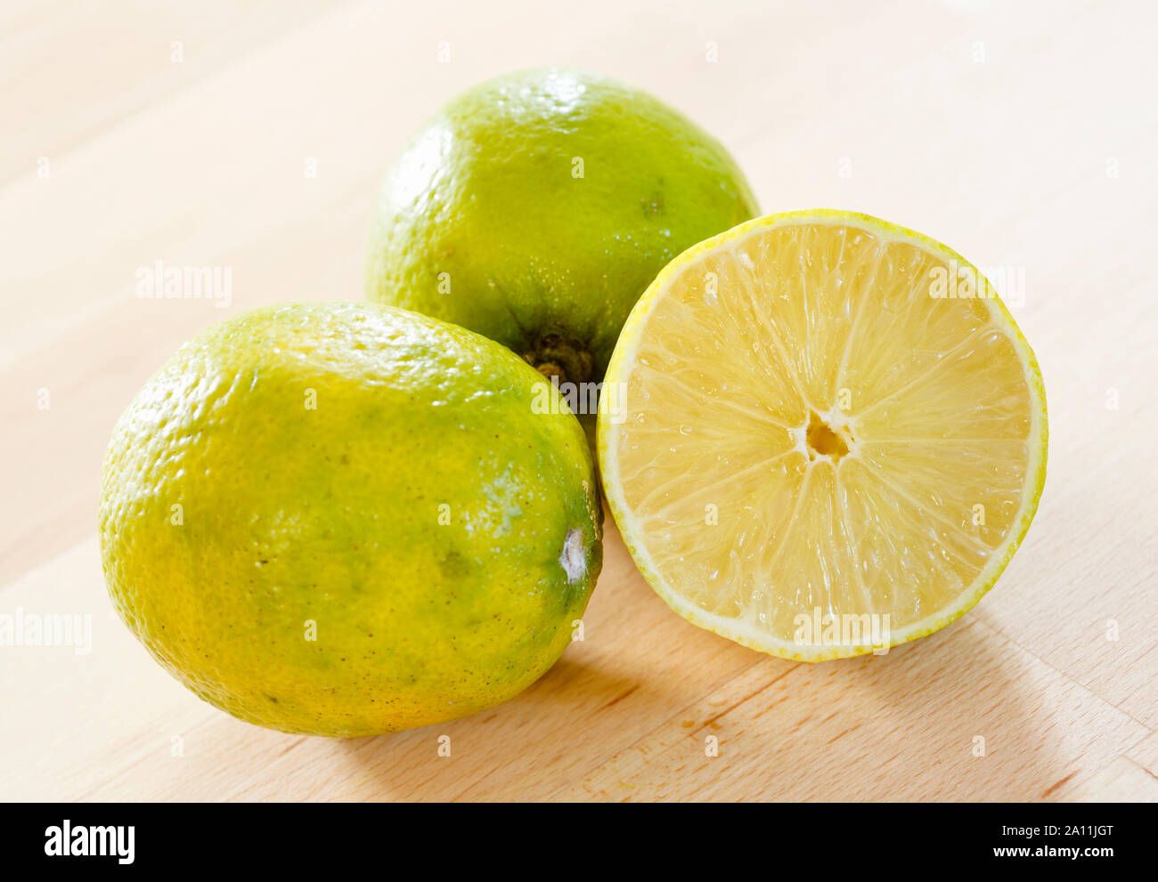 Limes su un tavolo di legno, intero e metà Foto Stock