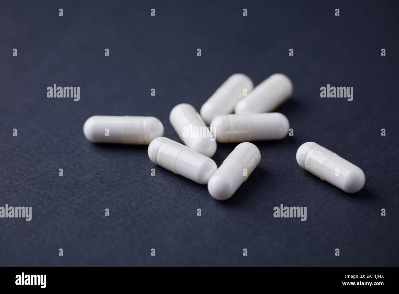 Le capsule di arginina. Carta scuro dello sfondo. Close up. Copia dello spazio. Foto Stock