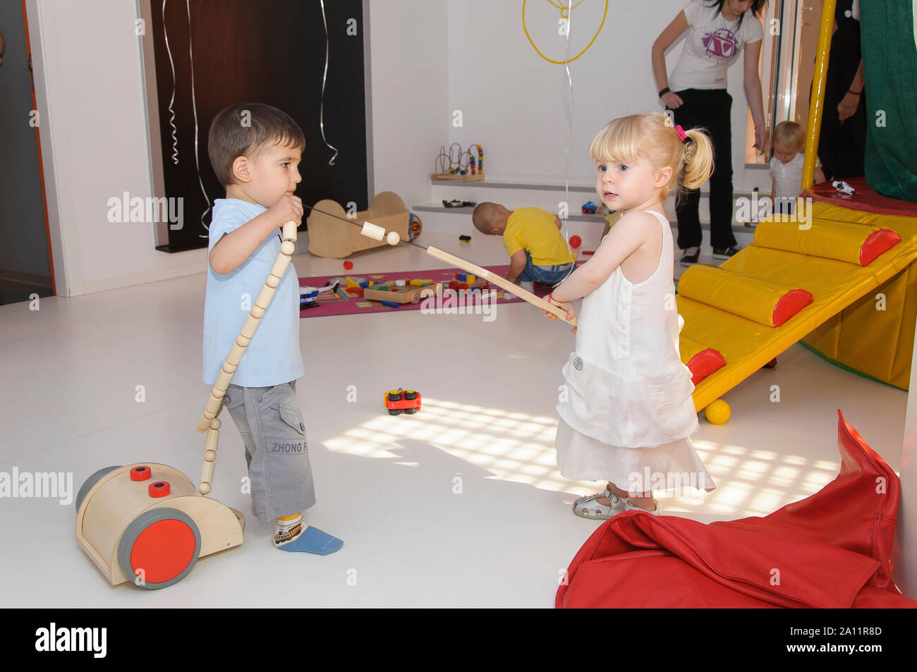 Autentica scena con un po' di bambini che giocano in interni con i giocattoli di legno in capretto il partito di centro parco giochi. Foto Stock