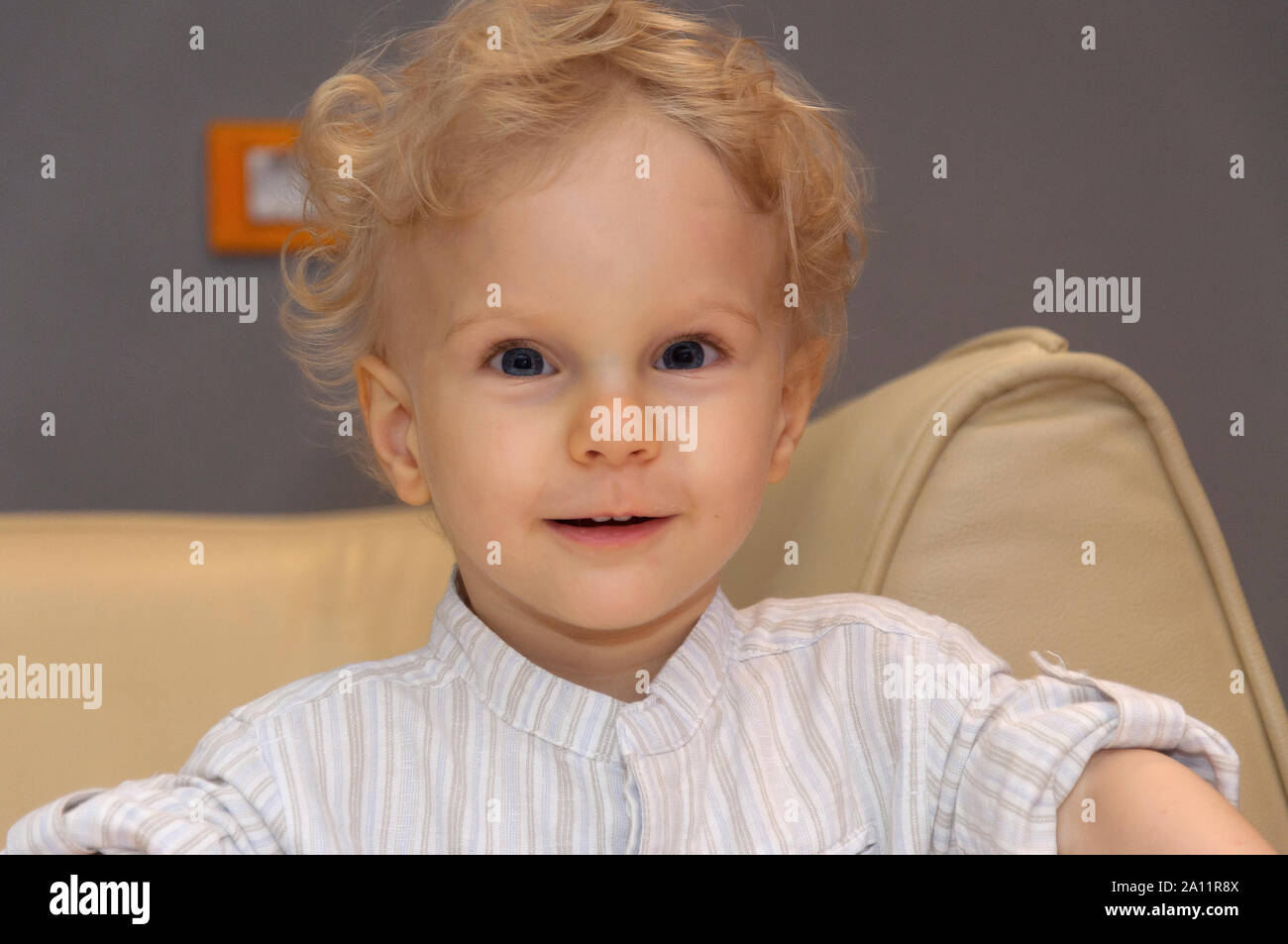 Candido autentico ritratto di un felice carino due anni di età, biondo capelli bambino ragazzo con occhi blu sorridente e guardando nella fotocamera. Foto Stock