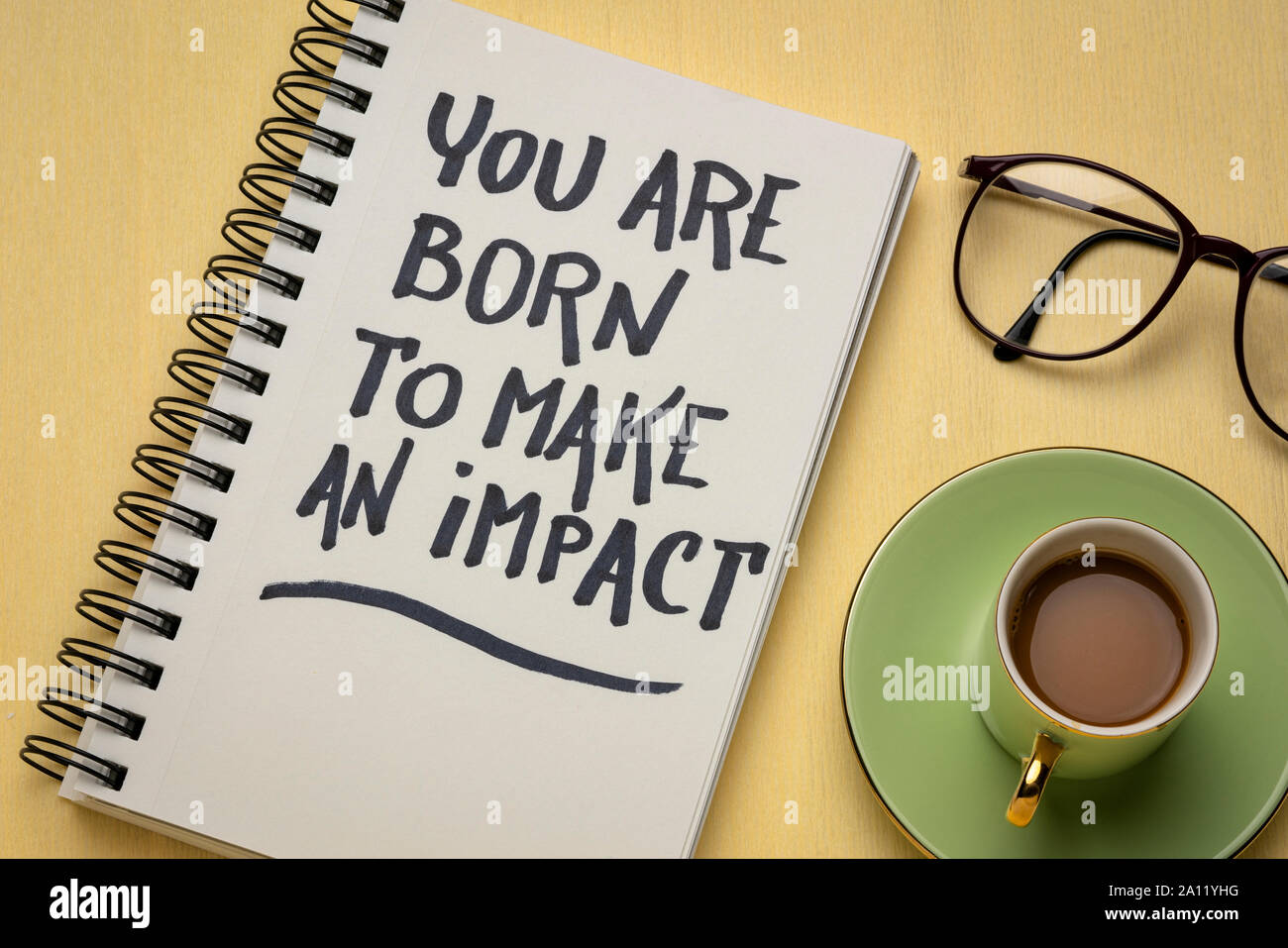 Siete nati per fare un impatto - ispirazione la grafia in un taccuino con una tazza di caffè, rendere un concetto di differenza Foto Stock