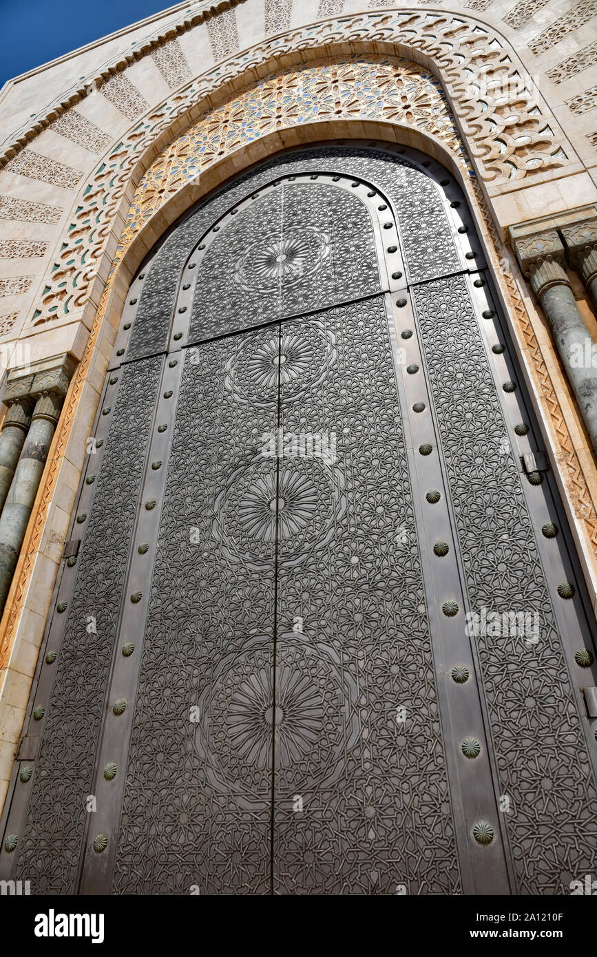 Arabesque arcuata a doppia porta, rivestita di bronzo inciso e titanio (antiruggine), ammette i visitatori della moschea di Hassan II, Casablanca, Marocco, Africa. Foto Stock