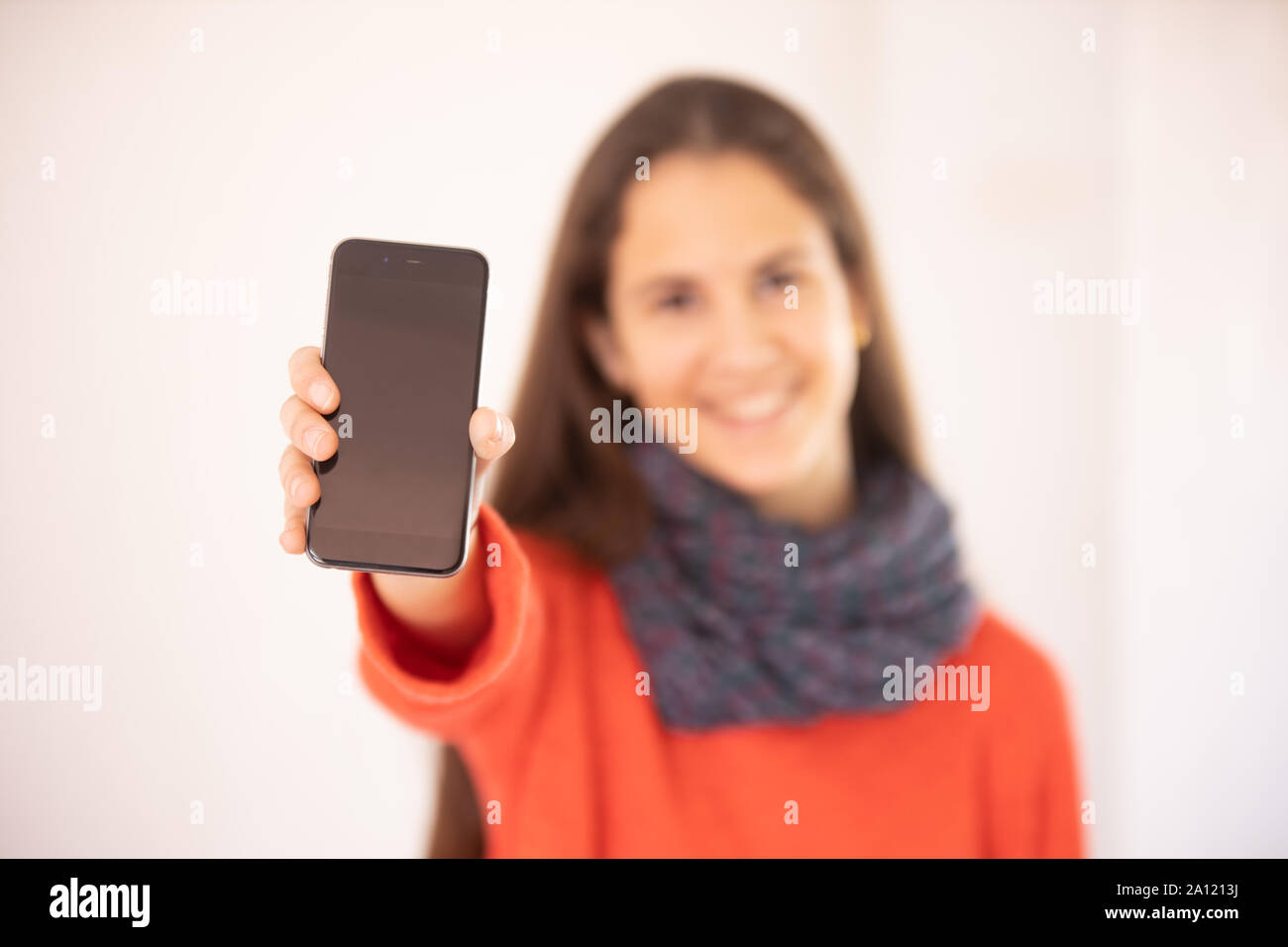Chica adolescente feliz mostrando una maqueta de teléfono inteligente Foto Stock