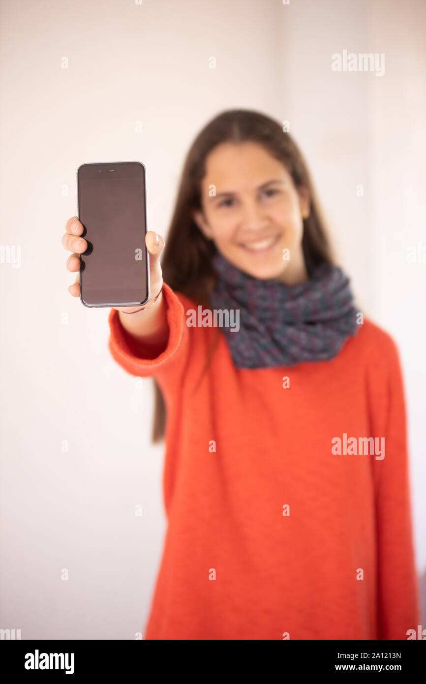 Chica adolescente feliz mostrando una maqueta de teléfono inteligente Foto Stock