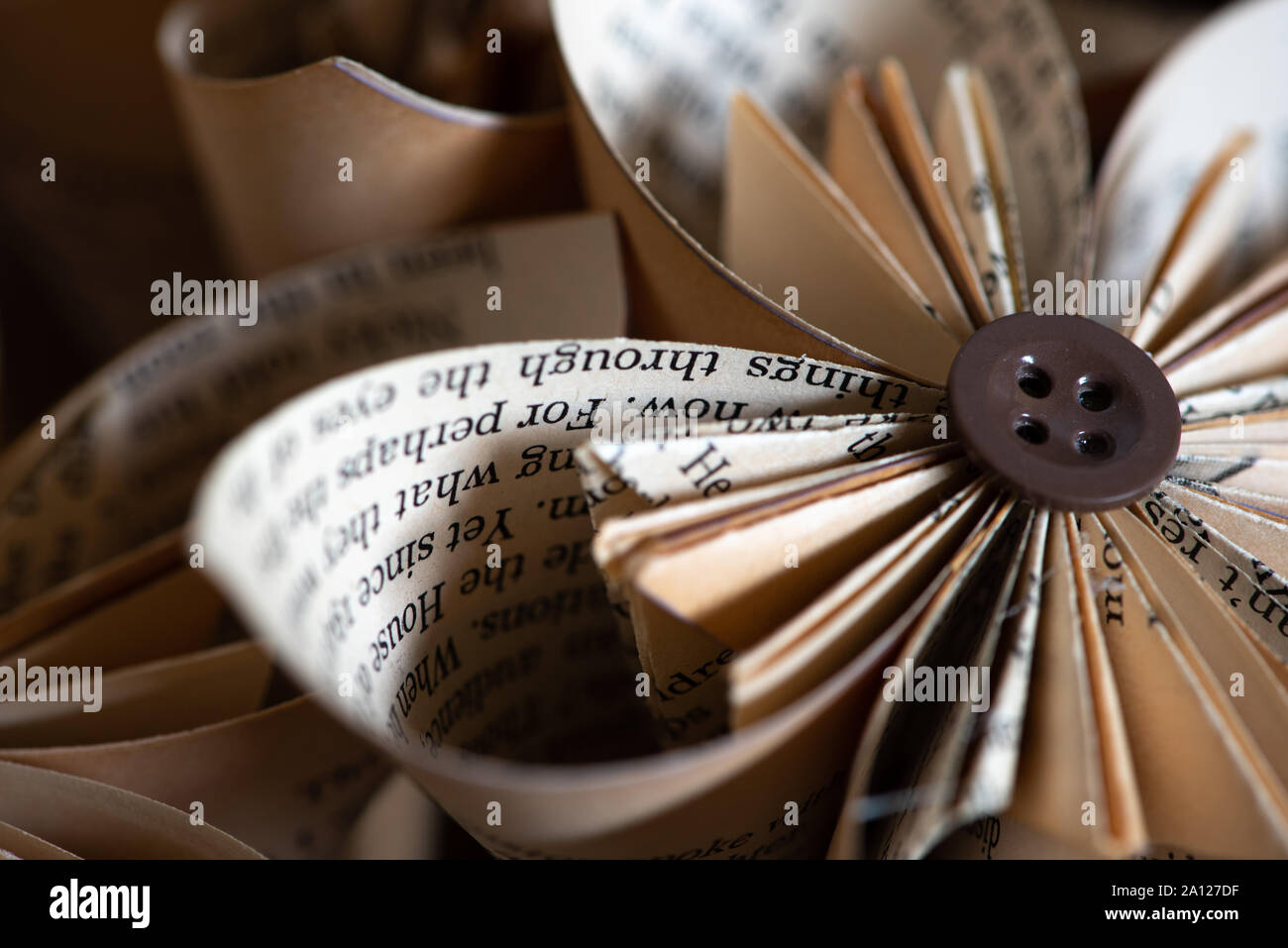 Elegante origami-tipo fatti a mano carta ripiegata fiori costruito da pulsanti e le pagine di un vecchio libro Foto Stock