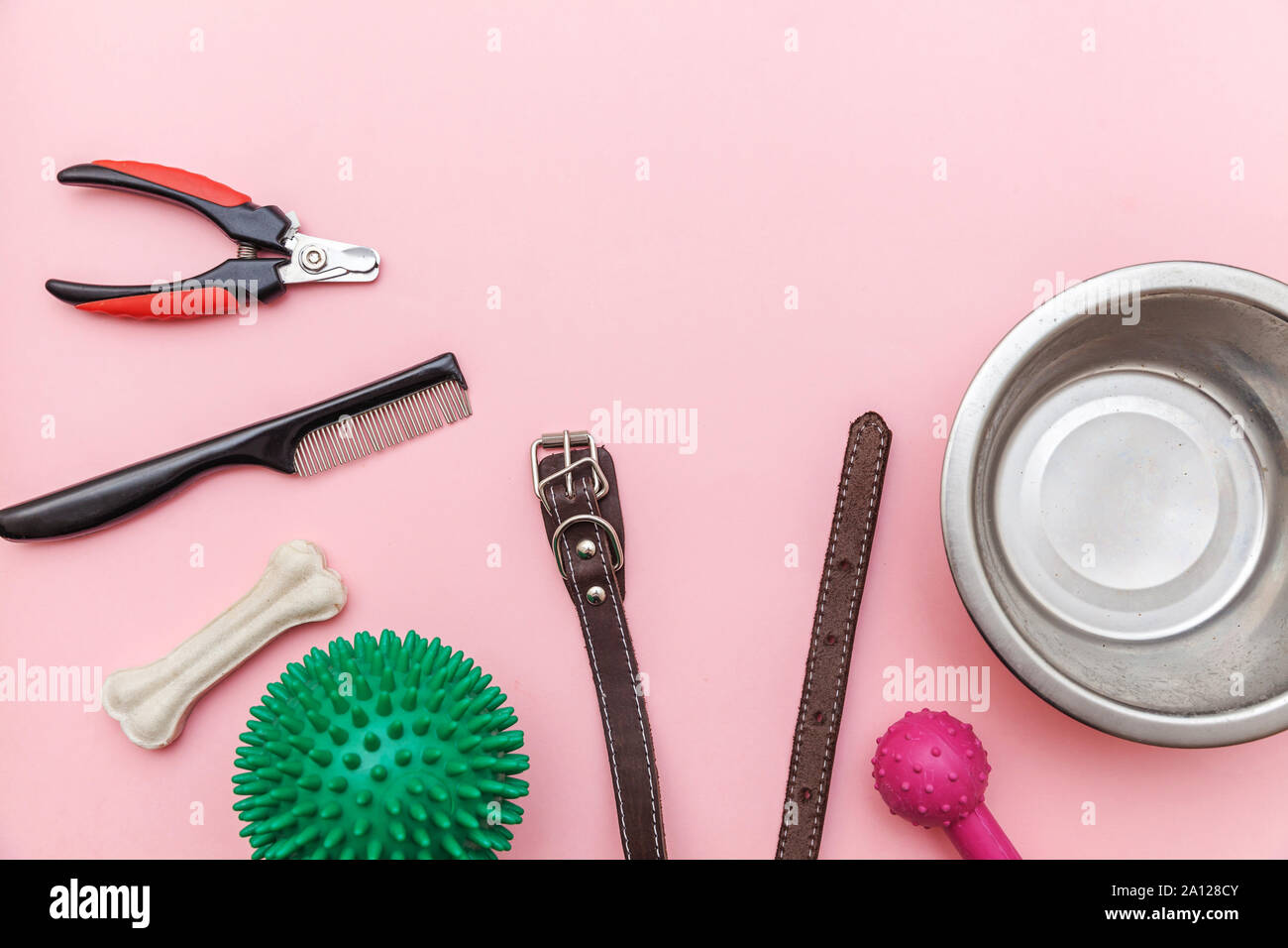 Pet care e concetto di animali. Giocattoli e accessori per cane per la riproduzione e la formazione isolato sul rosa pastello sfondo alla moda. Lay piatto con sfera di osso artiglio clicker piatto di taglio il collare. Vista dall'alto uno spazio di copia Foto Stock