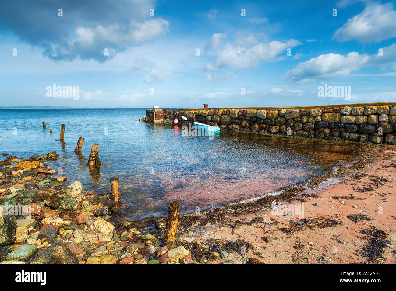 Una piccola barca ormeggiata in un antico molo di pietra a Sannox sull'isola di Arran in Scozia Foto Stock