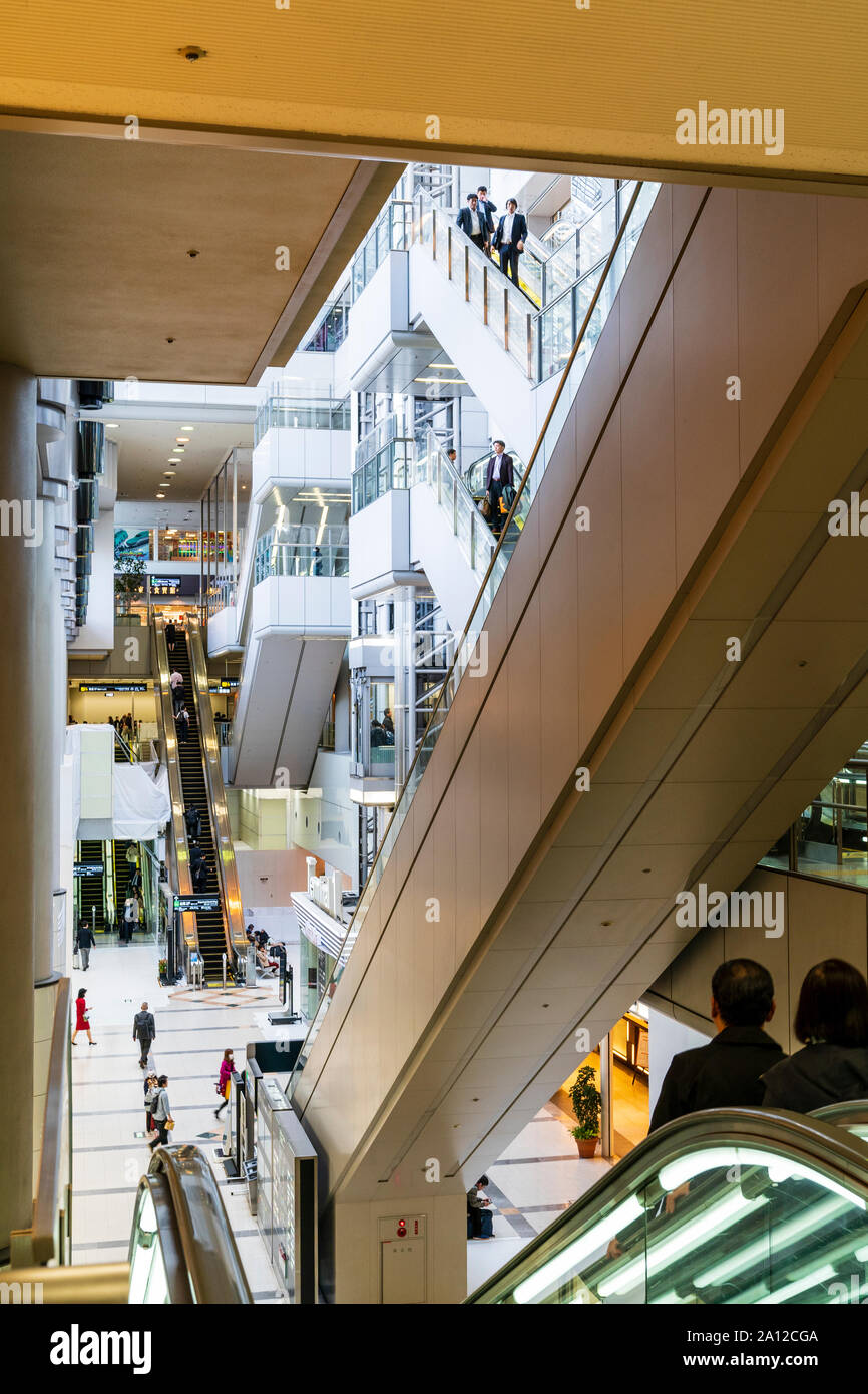 Tokyo Haneda interni. L'escalator centrale e la zona di sollevamento che serve i quattro piani del terminal uno, con scale mobili su entrambi i lati. Persone. Foto Stock