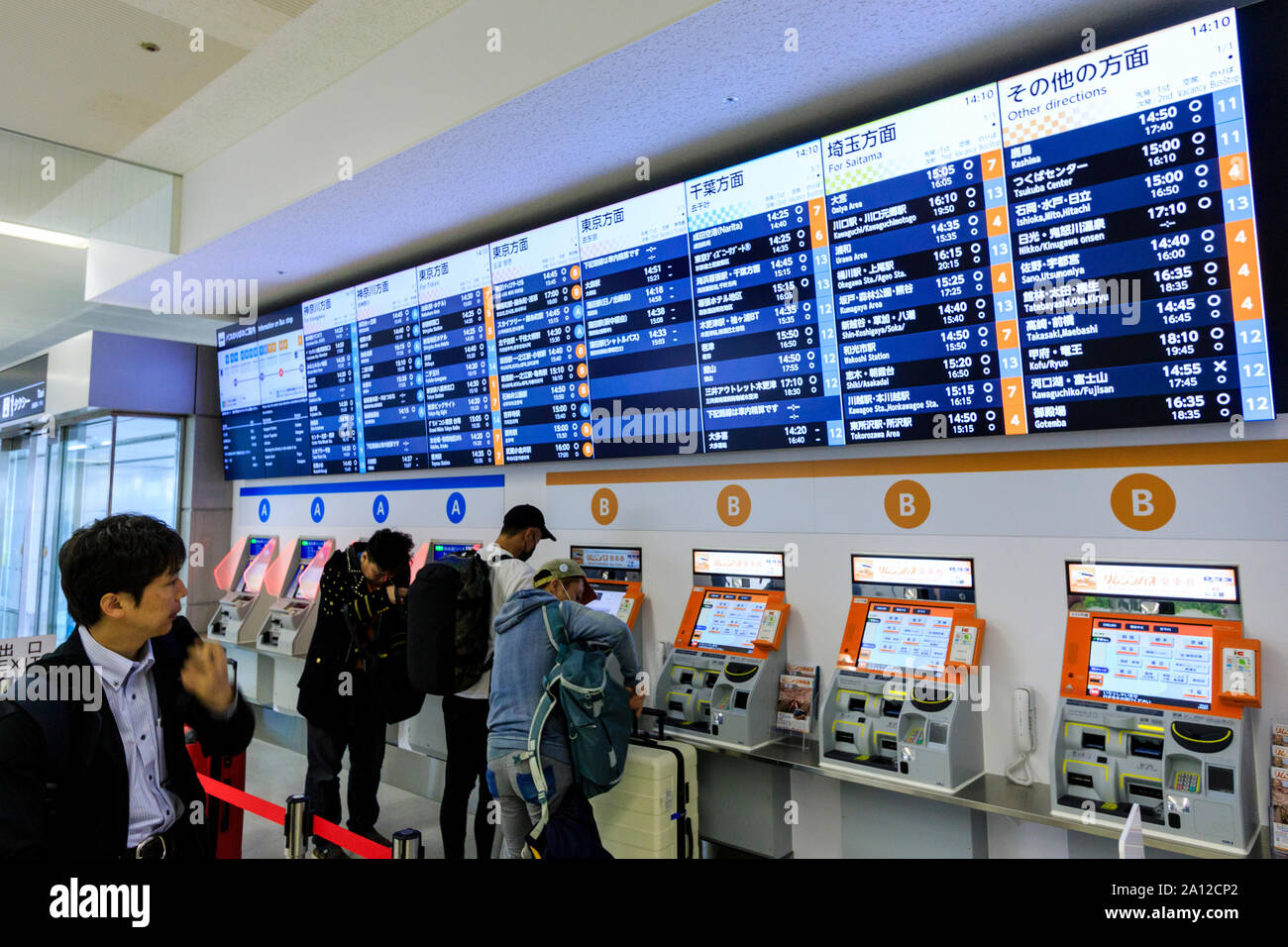 Tokyo Haneda international airport. Un terminale interno. Le persone che usano una fila di bus ticket macchine contrassegnate A e B, con calendario illuminata sopra. Foto Stock