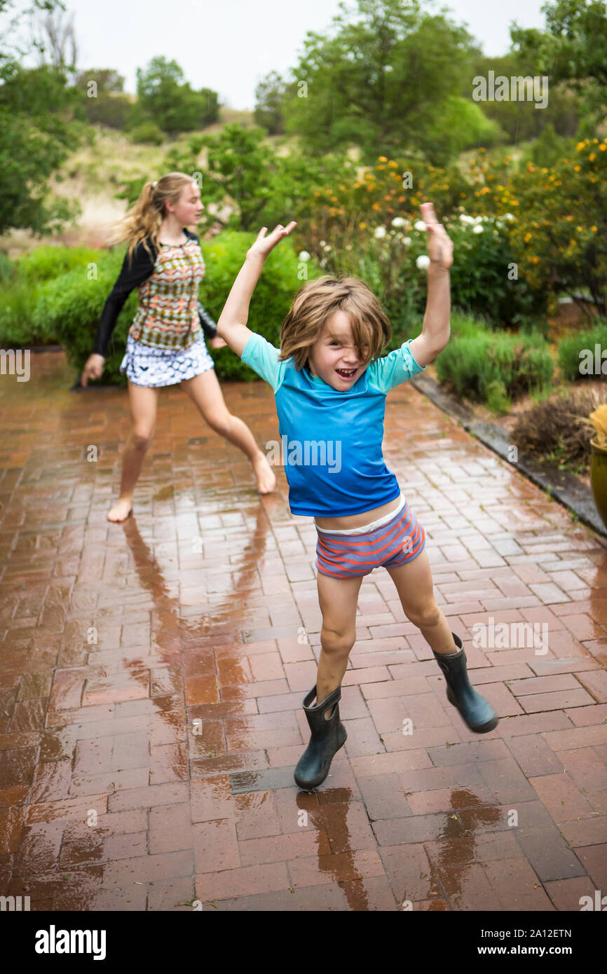 5 anno old boy e il suo 13 anni suor ballando sotto la pioggia. Foto Stock