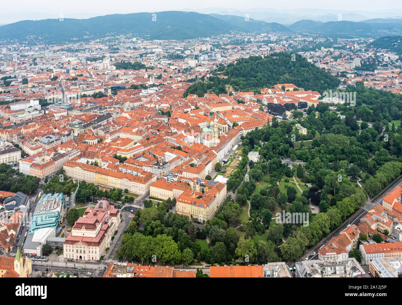 Vista aerea del centro città di Graz da elicottero drone con hill Schloßberg, torre Uhrturm e central park a un giorno di estate in Austria, Europa Foto Stock