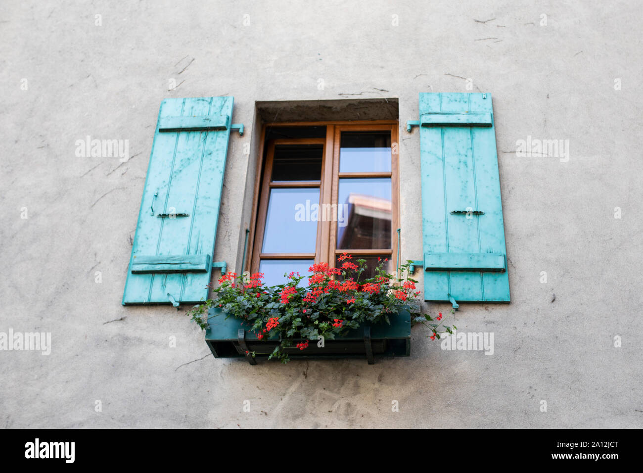 Verniciato colorato turchese tapparelle su una finestra con gerani nel borgo medievale di Yvoire, Haute-Savoie, Auvergne-Rhône-Alpes, Francia. Foto Stock