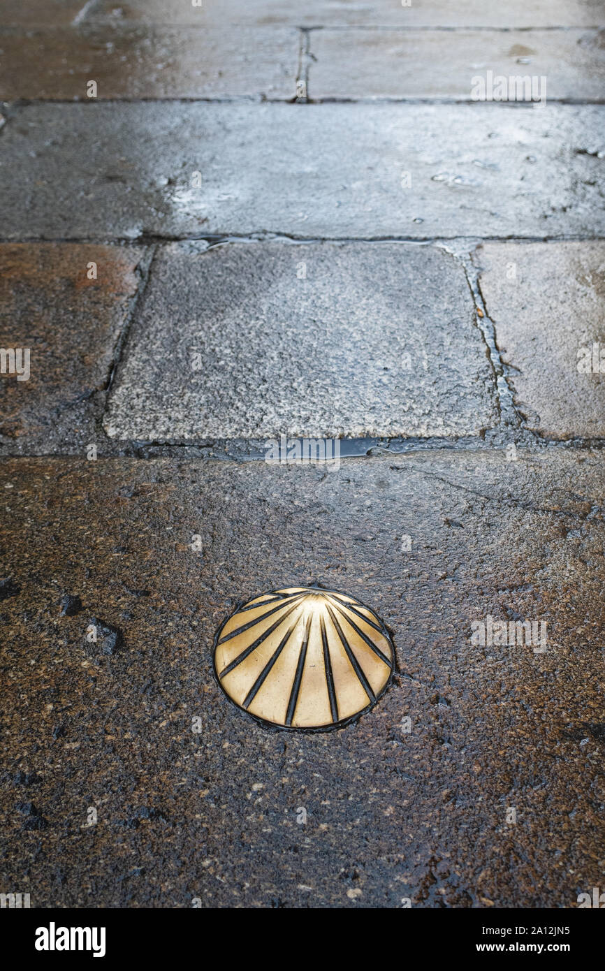 Camino de Santiago ottone St James Smerlo Shell sul pavimento bagnato in Santiago de Compostela, Spagna Foto Stock