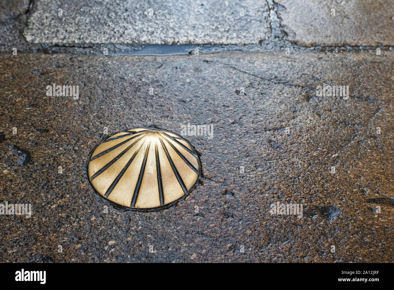 Camino de Santiago ottone St James Smerlo Shell sul pavimento bagnato in Santiago de Compostela, Spagna Foto Stock