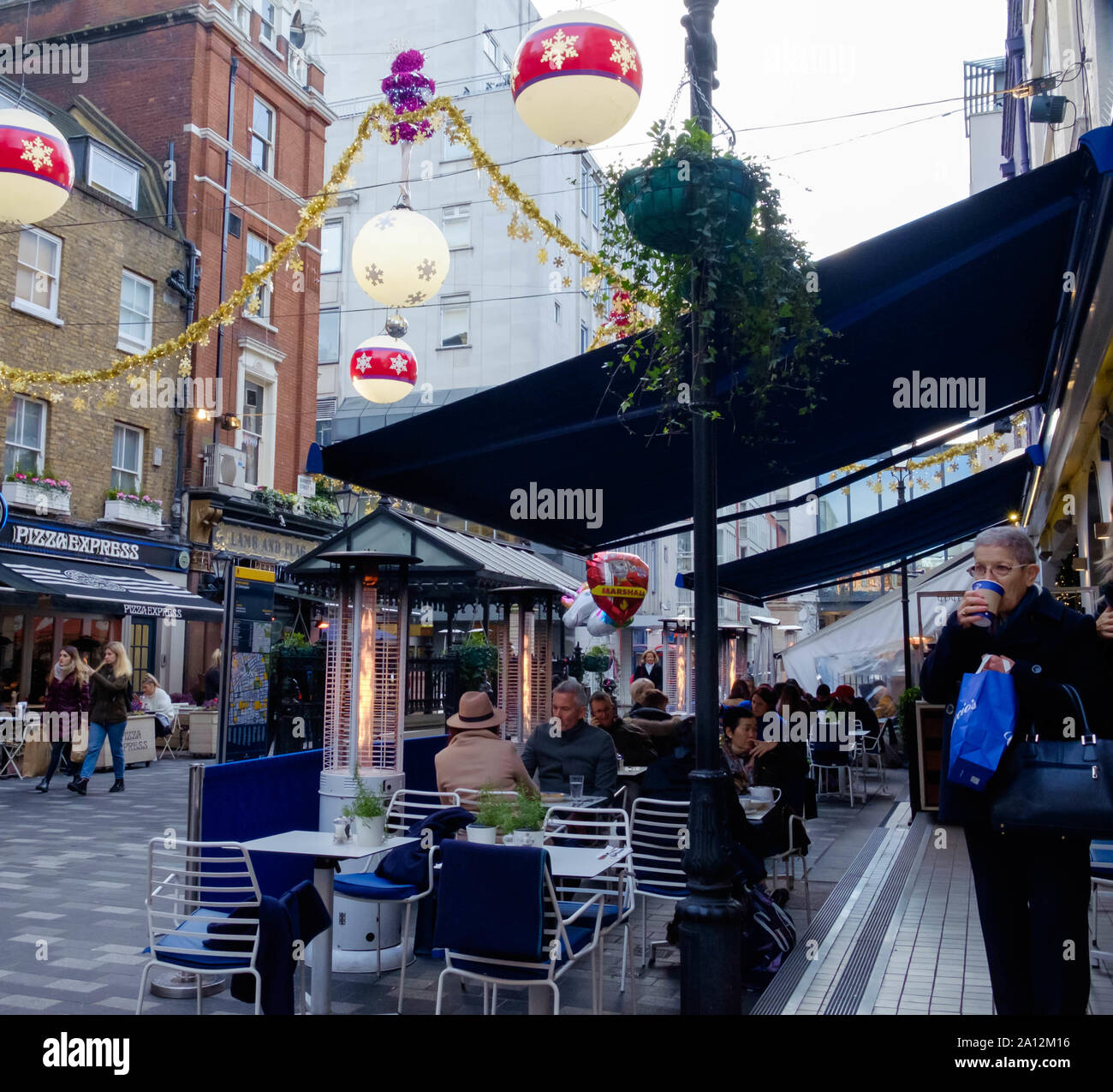 I londinesi e turisti Mangiare & bere a al di fuori dei ristoranti & shop. St. Christopher's Place, trendy open air area dello shopping, Londra centrale, tempo di Natale Foto Stock