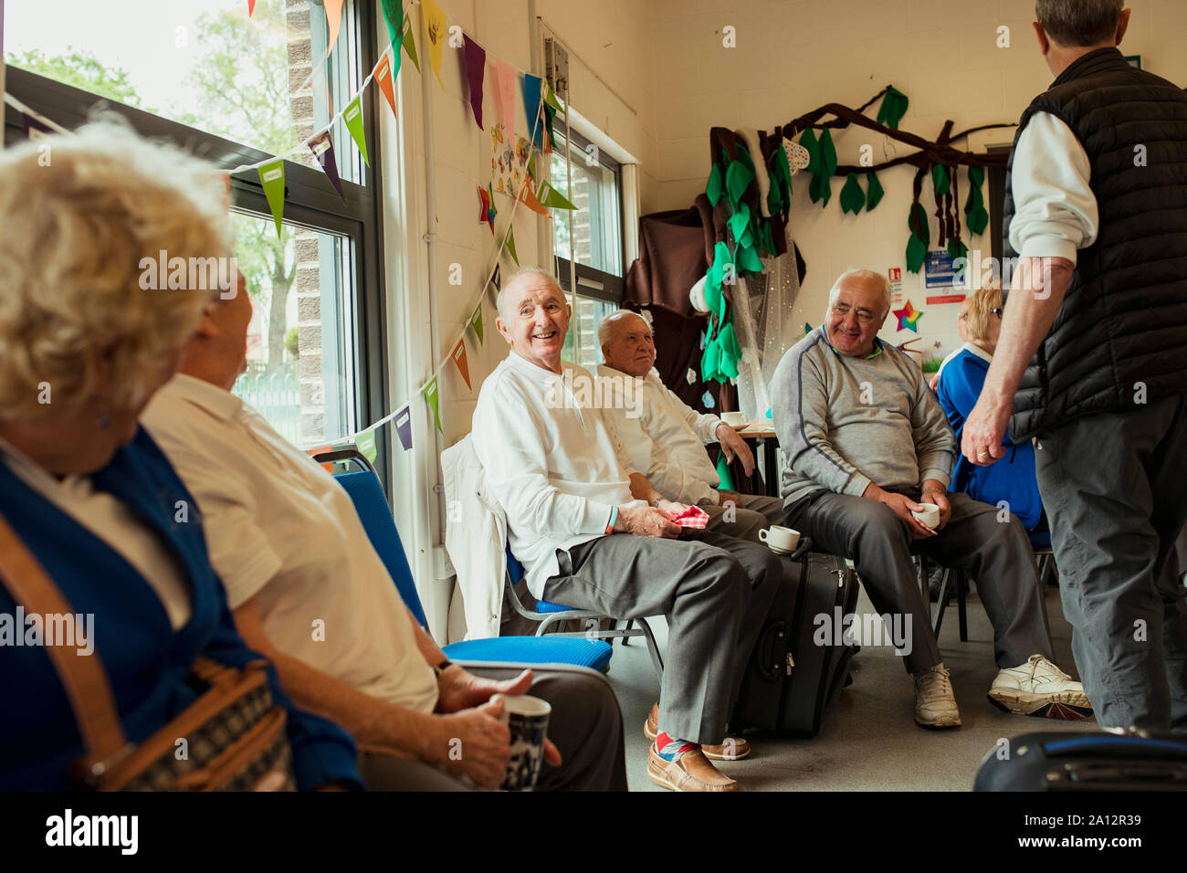 Un gruppo di anziani adulti seduti in ambienti chiusi e il legame con l'altro. Foto Stock
