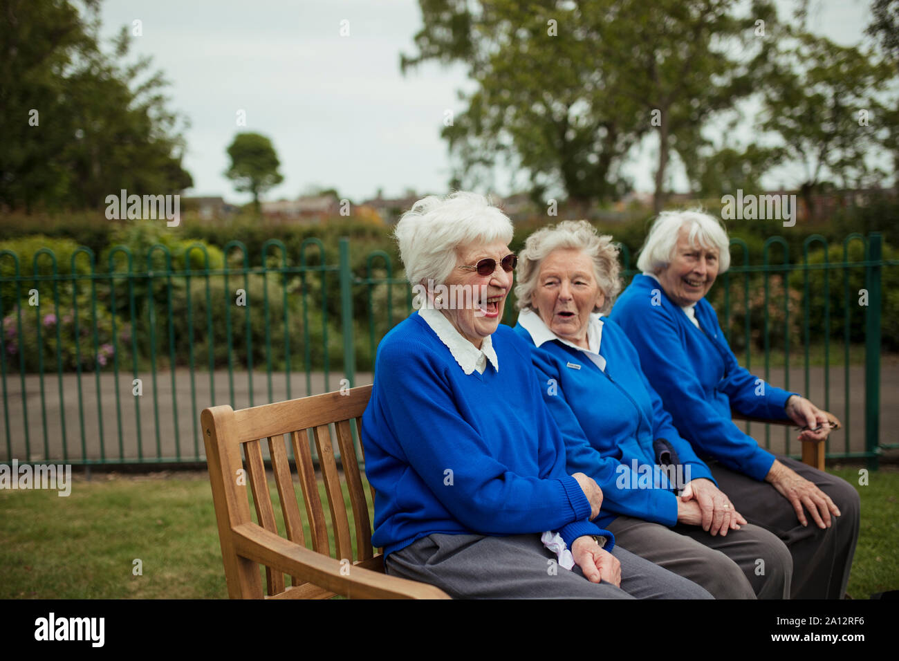 Una inquadratura ravvicinata di senior donna seduta su una panchina a bowling green a ridere. Foto Stock