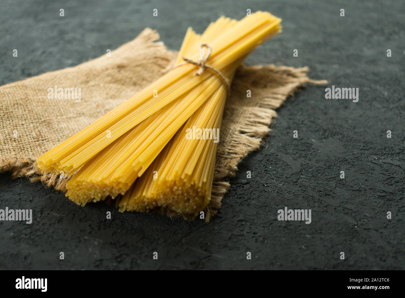 Materie spaghetti legato con una corda su una texture nera dello sfondo. Copia dello spazio. Foto Stock