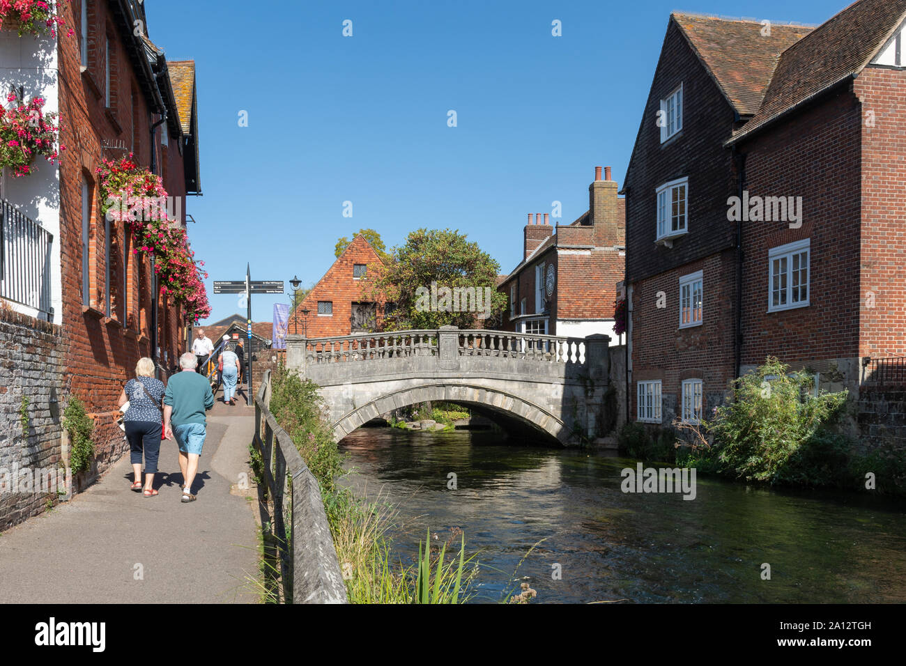 I visitatori a piedi dal fiume Itchen in Winchester dal centro città in una giornata di sole, Hampshire, Regno Unito Foto Stock