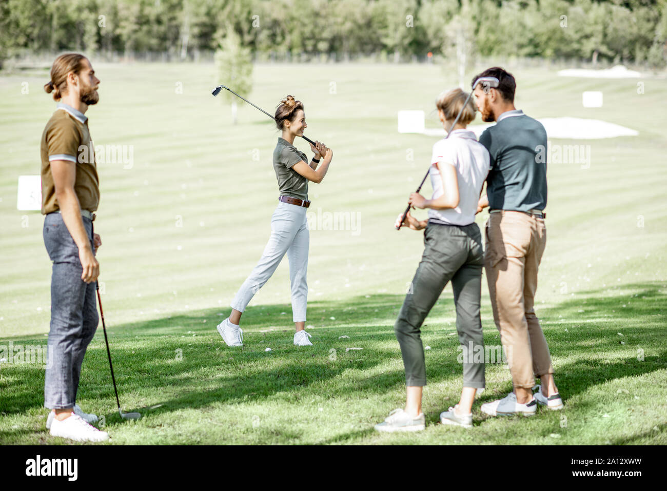 Gruppo di un popolo giovane vestito casualmente per giocare a golf sul  bellissimo campo da golf in una giornata di sole, donna oscillazione un  putter Foto stock - Alamy