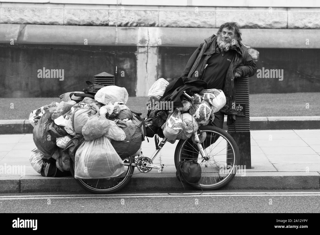 Un senzatetto per le strade del centro di Londra con la sua intera averi trasportati in sacchetti di plastica su un ciclo. I senzatetto uomo ha dato il suo consenso per questa fotografia di essere preso di lui. Il colpiti dalla povertà uomo disse che aveva vissuto per le strade per quattro [ 4 ] anni. Foto Stock