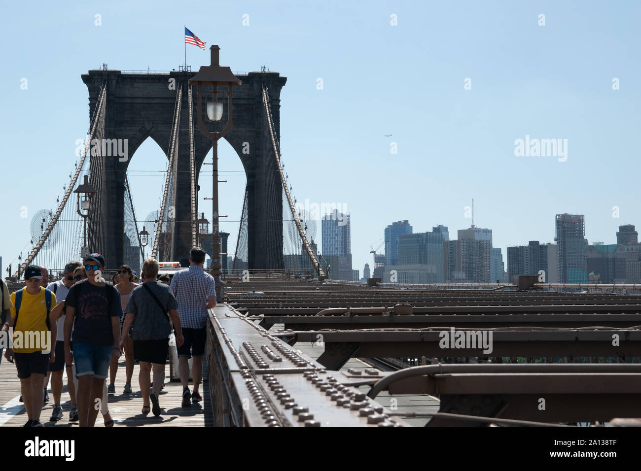 Menschen überqueren die Brroklyn Bridge, weil sie sowohl eine tolle Aussicht auf Brooklyn als auch auf die Skyline von Lower Manhattan bietet. Foto Stock