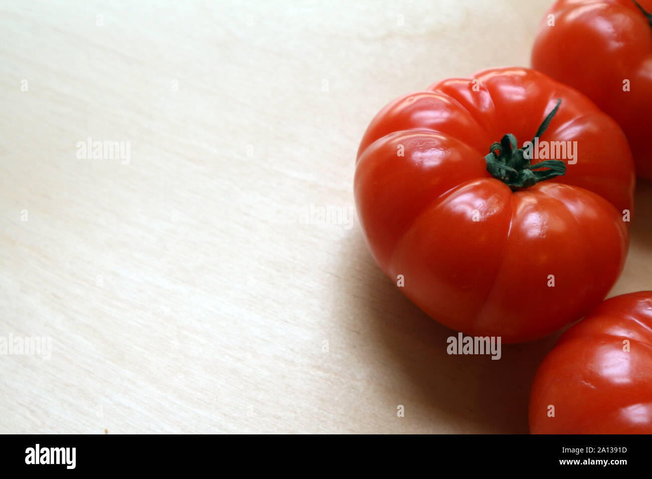 Grandi rossi maturi pomodori interi sul tagliere Foto Stock