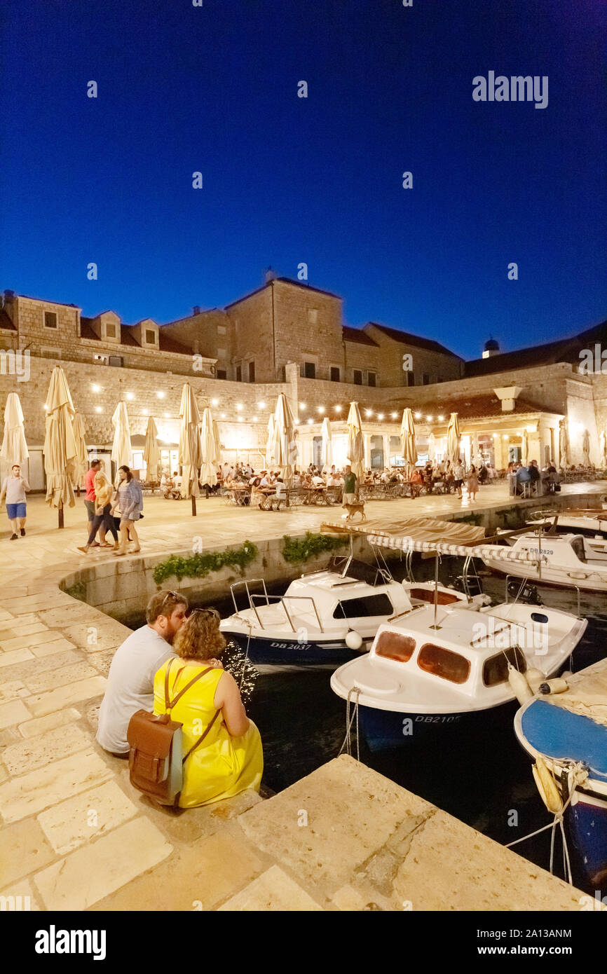 Dubrovnik Vacanze: turista giovane seduto nel vecchio porto di sera, Dubrovnik Città Vecchia, sito patrimonio mondiale dell'UNESCO, Dubrovnik Croazia Europa Foto Stock