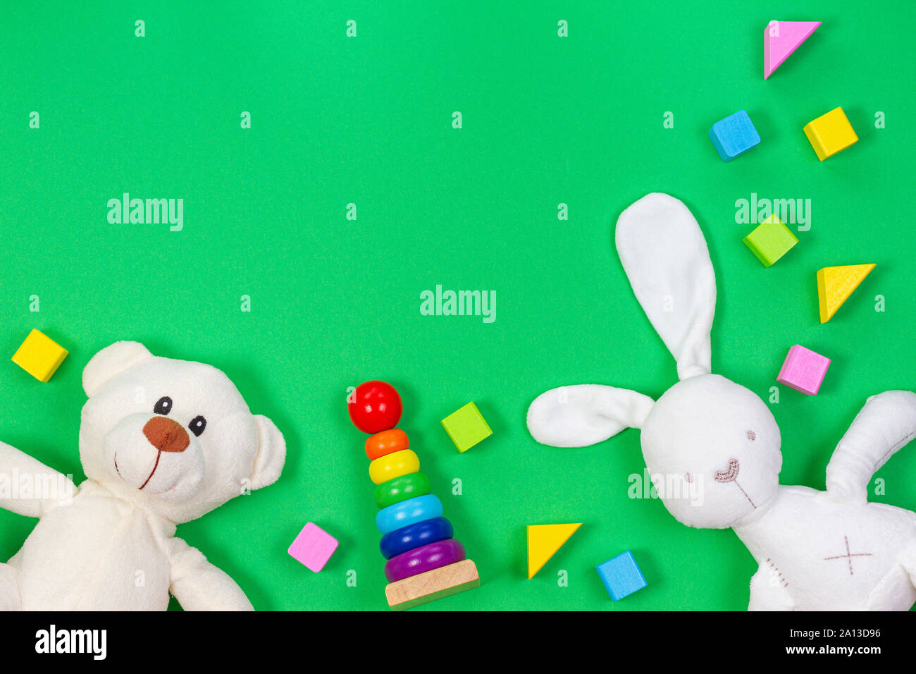 Baby giocattoli per bambini lo sfondo con un orso di peluche morbido peluche e giocattoli di legno e blocchi su sfondo verde chiaro. Foto Stock