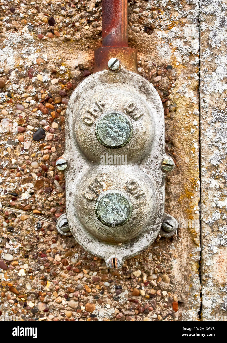 Un vintage retrò in metallo tipo twist on off esterna interruttore luce con trunking fuori la cima montata su un blocco di brezza parete capannone Foto Stock