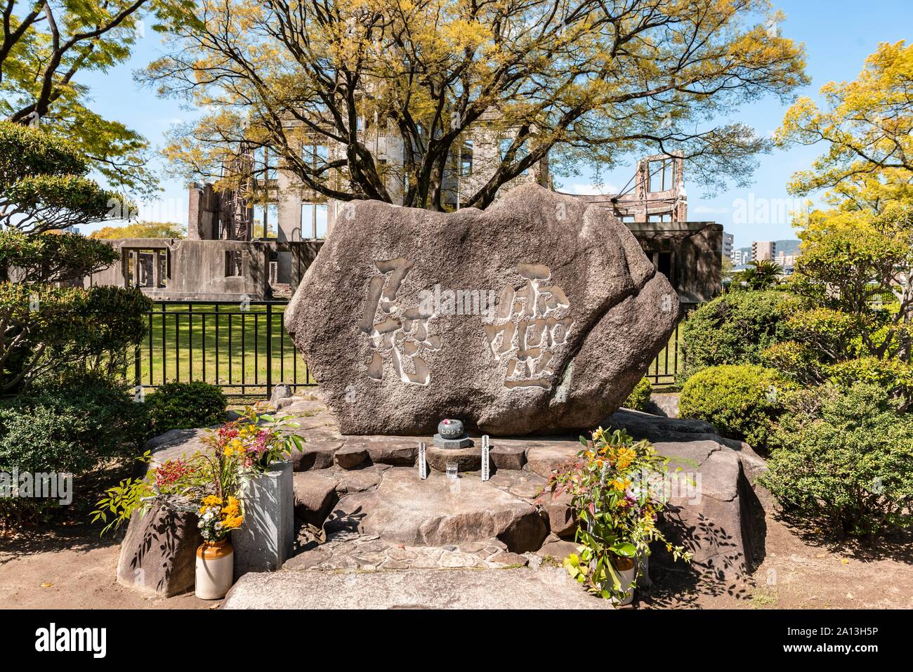 Pietra per commemorare le bombe atomiche durante la II Guerra Mondiale, la cupola della bomba atomica sul retro, monumento della pace di Hiroshima e il Parco della Pace di Hiroshima, Giappone Foto Stock