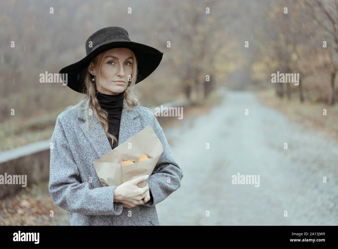 La donna a ricoprire e hat sotto la pioggia Foto Stock