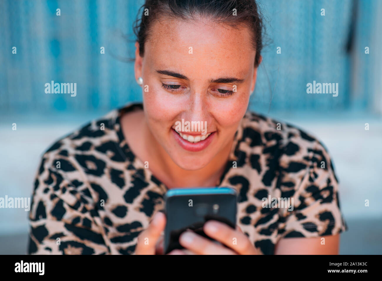 In prossimità di una donna felice sorridente utilizzando uno smartphone all'esterno. Foto Stock