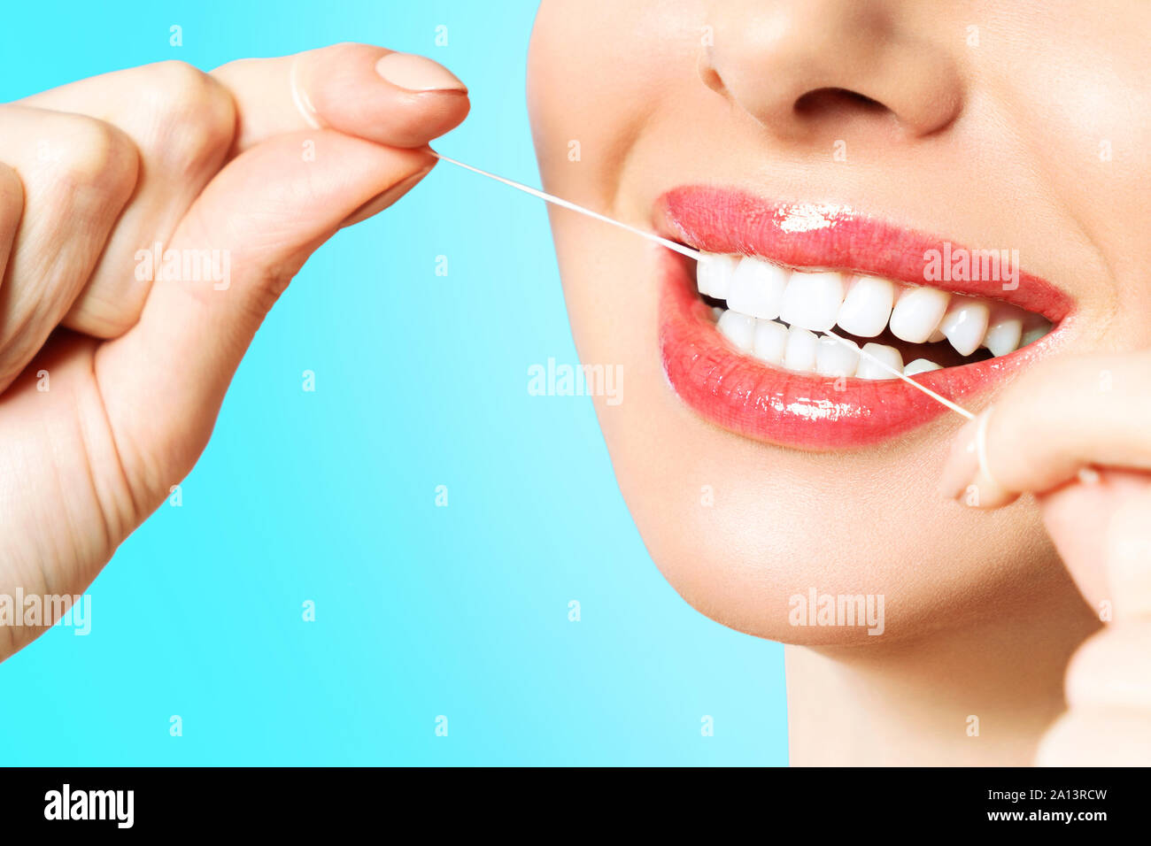 Giovane bella donna è impegnato nella pulizia dei denti. Bel sorriso Denti sani denti bianchi. Una ragazza detiene un filo interdentale. Il concetto di igiene orale. Foto Stock
