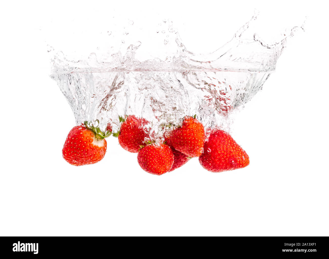 Le fragole di cadere in acqua causando bolle tutto intorno. Cibo sano concetto Foto Stock