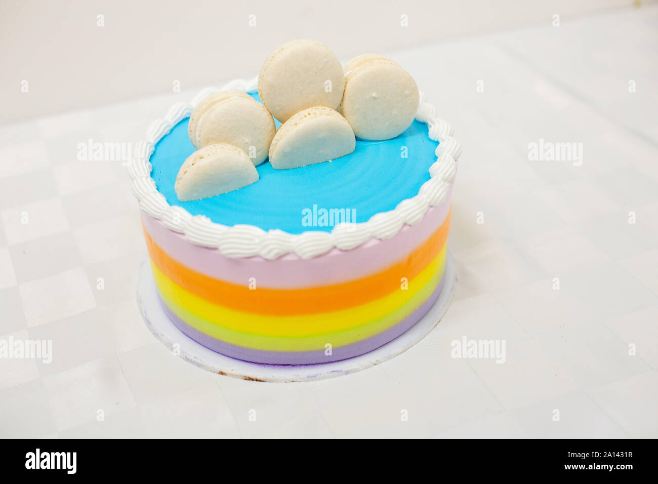 Rainbow torta stratificata con macarons sulla parte superiore su sfondo bianco Foto Stock