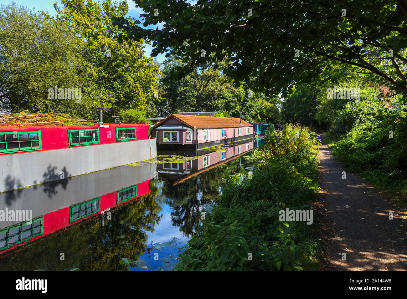 Casa galleggiante rosso permanentemente ormeggiato sulle rive del Basingstoke Canal nel Woodham area di Woking, Surrey, Inghilterra sudorientale, REGNO UNITO Foto Stock