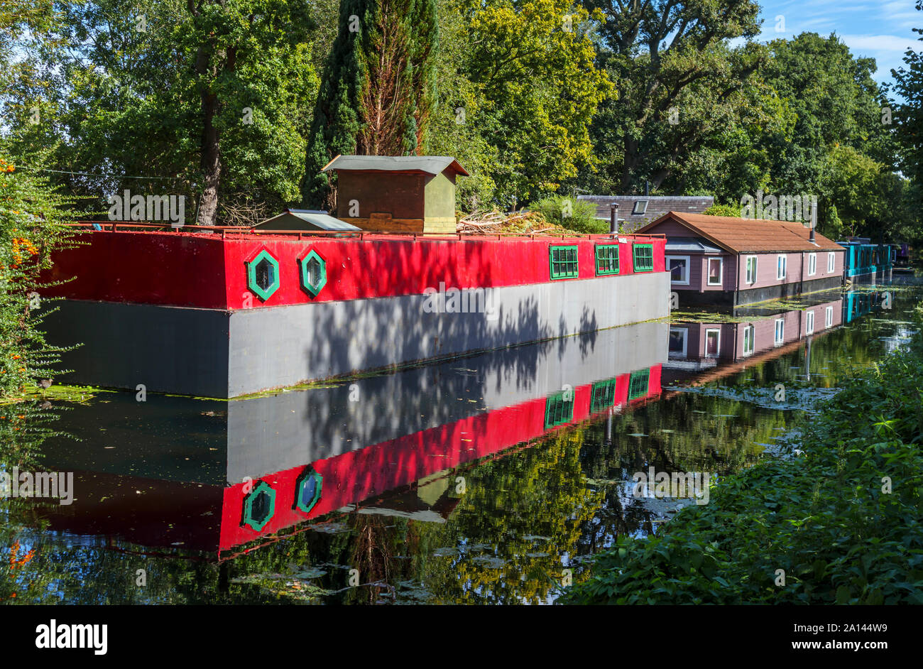 Casa galleggiante rosso permanentemente ormeggiato sulle rive del Basingstoke Canal nel Woodham area di Woking, Surrey, Inghilterra sudorientale, REGNO UNITO Foto Stock