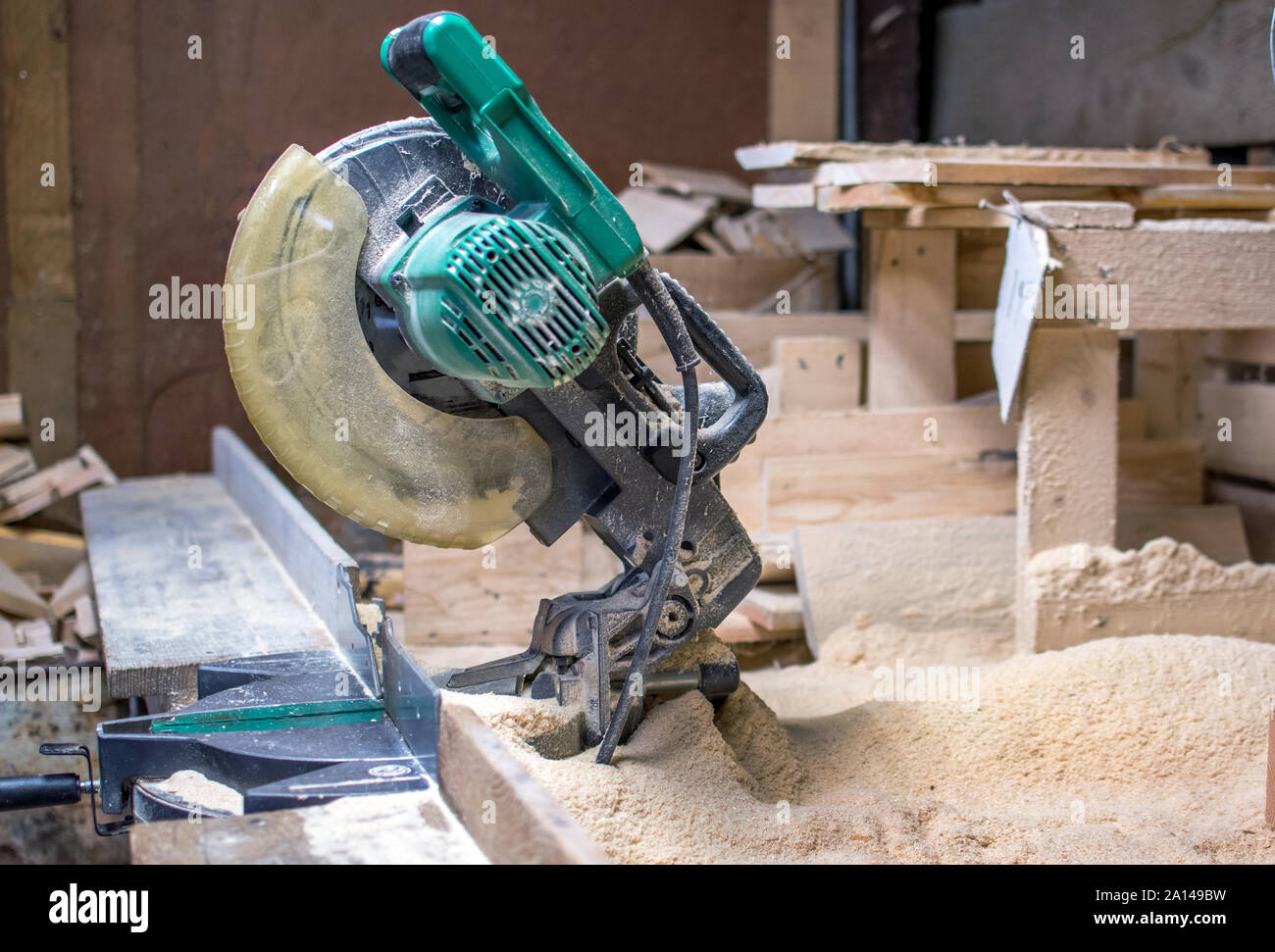 Una troncatrice si siede in un mucchio di segatura, in un legno lavoratori work shop Foto Stock