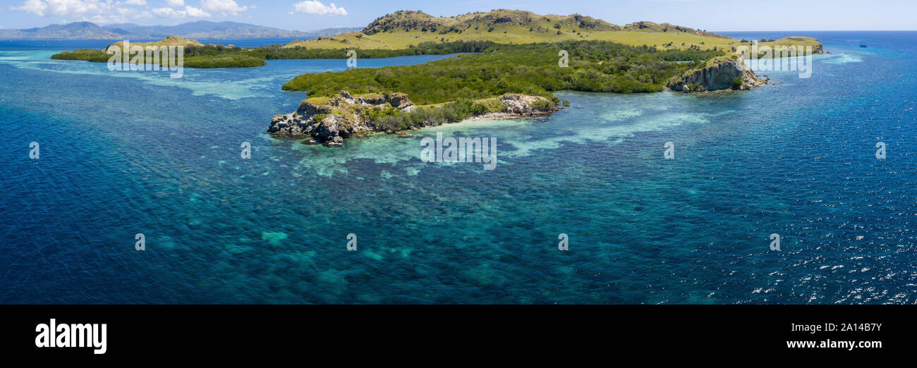 Vista panoramica di un'isola idilliaca e barriera corallina nel Parco Nazionale di Komodo, Indonesia. Foto Stock