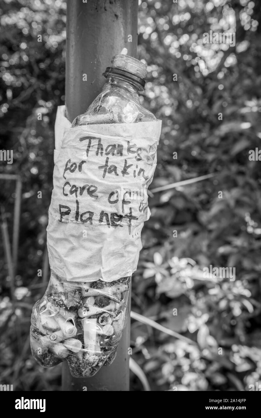 La bottiglia di plastica con un messaggio 'Grazie per aver cura del nostro pianeta' pieno di mozziconi di sigarette. Idea per evitare di inquinare l'ambiente. Foto Stock