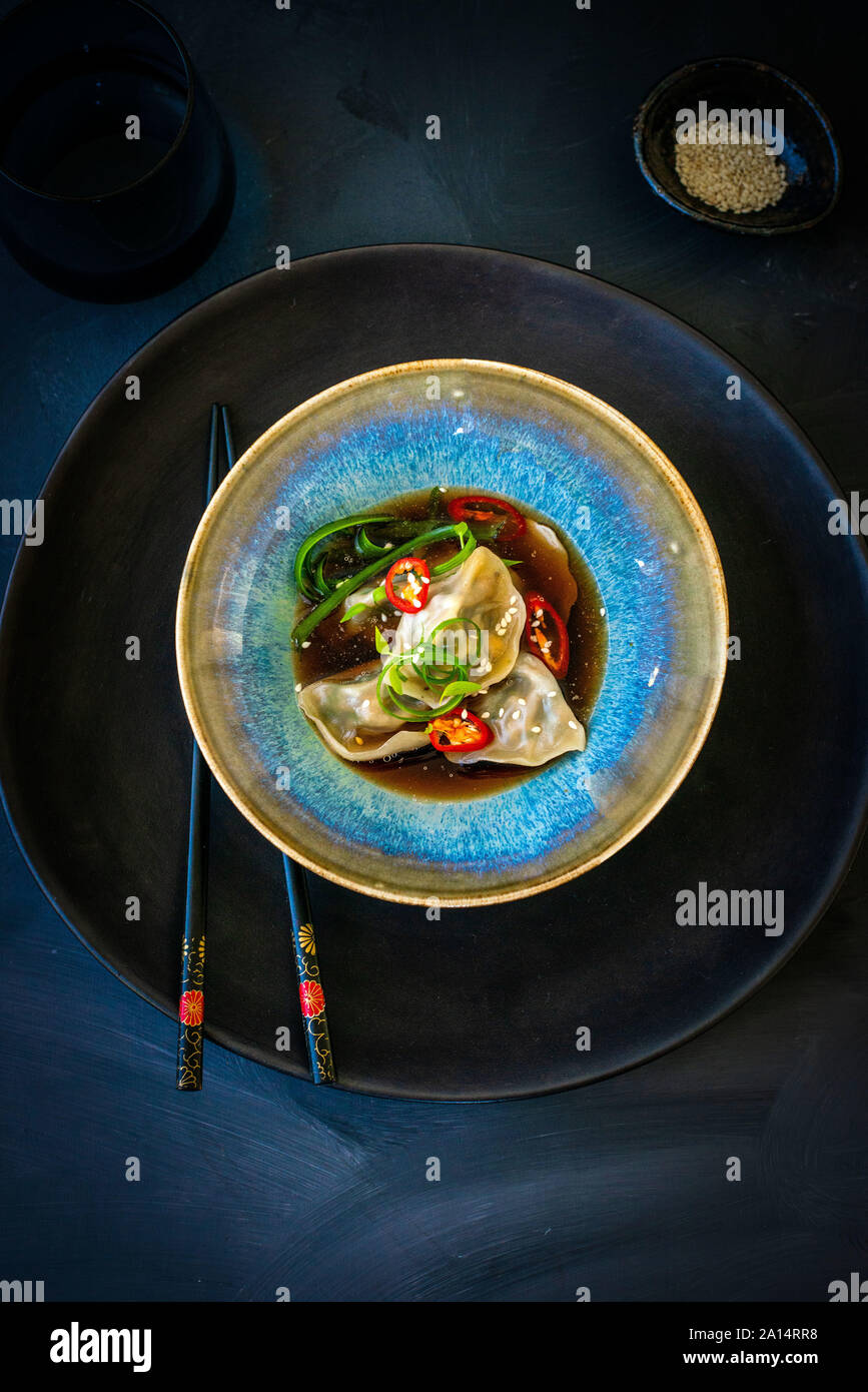 Asian canederli in brodo con chilis e bastoncini su sfondo scuro Foto Stock